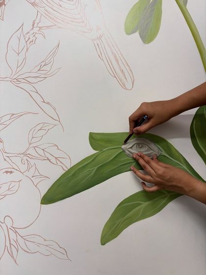 Adding the final shading to a painted leaf, right next to where a sculptural eye will be placed. The process involves a constant interplay between different mediums and techniques.