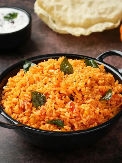 The rich color of this Tomato Rice is its main appeal. We used dark, moody lighting to make the colors pop and highlight the fresh curry leaves, making a simple dish look exceptionally flavorful.