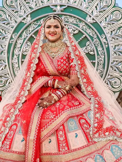 A majestic portrait of the bride seated, showcasing the grandeur of her entire ensemble. The makeup remains a focal point, tying together the colors of her outfit and the magnificent decor.