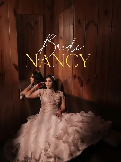 A beautiful portrait of the bride, Nancy, on her Roka day. She leans against a mirror in a room with warm wood paneling, her ruffled gown and thoughtful expression creating an elegant and artistic image.