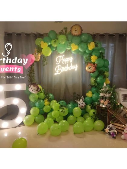A fun jungle-themed 5th birthday. The room is filled with green balloons, animal foil balloons, and a large marquee number "5".