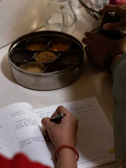 The best recipes are born from observation and scribbled notes. Here, a family recipe is being documented right in the heart of the kitchen, next to the masala dabba. Our journals are designed to be used, to gather stains and stories, and to become a living document of a family's culinary history.