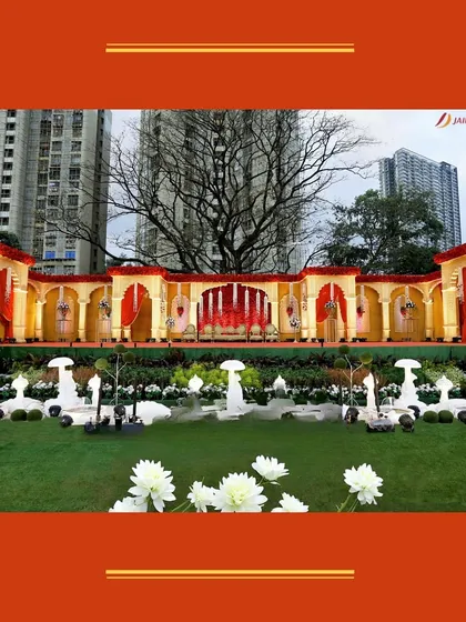 A wide shot of the royal red and gold wedding decor, showing the scale and grandeur of the design. The fountains in the foreground add a touch of serenity to the opulent setting.