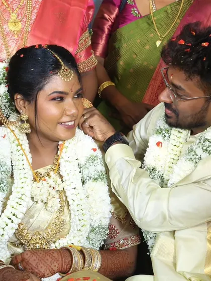 A candid moment of the groom affectionately touching the bride's chin during their wedding ceremony. Her makeup looks flawless and natural.