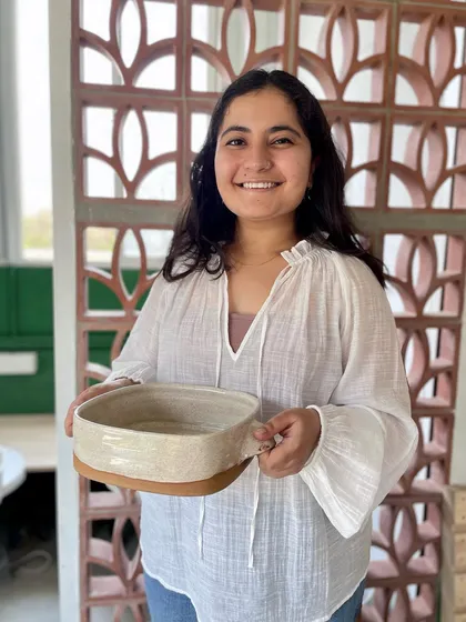 A proud portrait of Mansa with her work, ready for her graduation showcase.