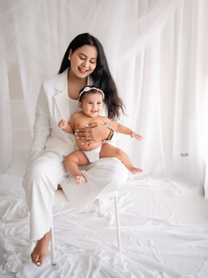 A mother holding her smiling baby on her lap.