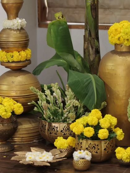 A close-up of the decor details, featuring stacked brass pots (kalash), marigolds, and banana leaves. These elements bring a sense of tradition and auspiciousness to the event.