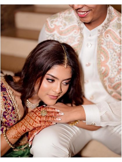 A close-up shot focusing on the bride's beautiful henna and the gentle way she holds her partner's hand.