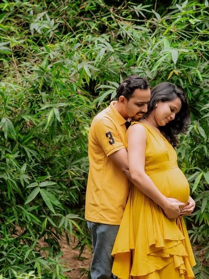 A tender embrace between partners, surrounded by the lush greenery of a park. This outdoor maternity portrait is filled with warmth and love.