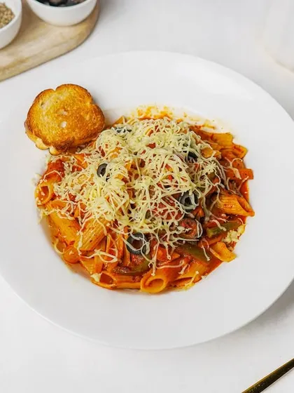 A top-down view of a plate of red sauce penne pasta, covered in cheese. The clean white background and simple props make this a versatile image for any Italian restaurant's marketing.