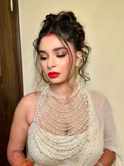 The bride's full look with the tousled high bun, paired with a statement pearl blouse and bold red lip.