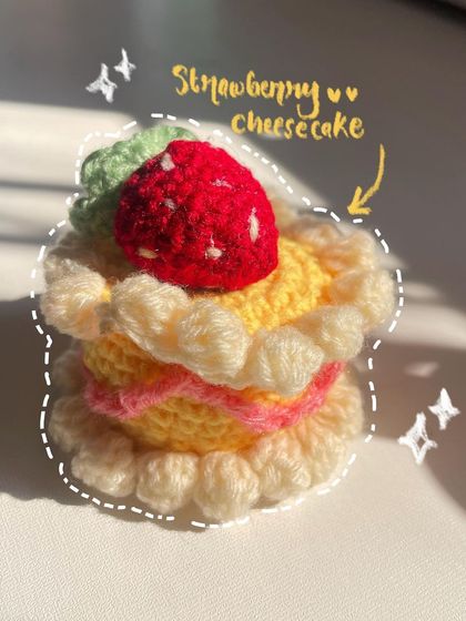 A close-up, annotated photo of the crochet strawberry cheesecake, showing off its cute and delicious-looking details.