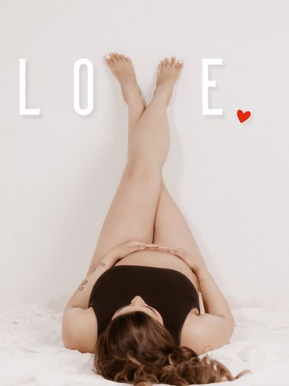 A creative and modern shot, capturing a unique perspective of the baby bump with a graphic "LOVE" overlay.