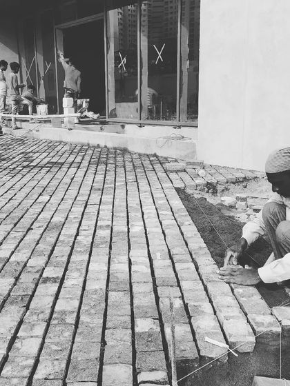 The satisfaction of seeing a design come to life is immense. This black and white photo captures a mason meticulously laying reclaimed bricks for a patio, a craft that adds timeless character to the space.