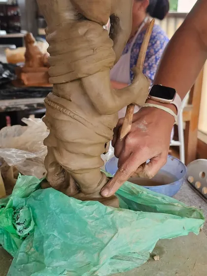 A close-up showing me guiding a student's hands as they add details to their Ganesha. It's a very hands-on learning experience.