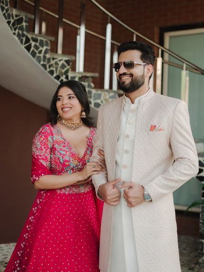 A stylish shot of the couple walking together at their Mehendi. Their coordinated pink and white outfits, along with their confident smiles, create a chic and modern portrait.
