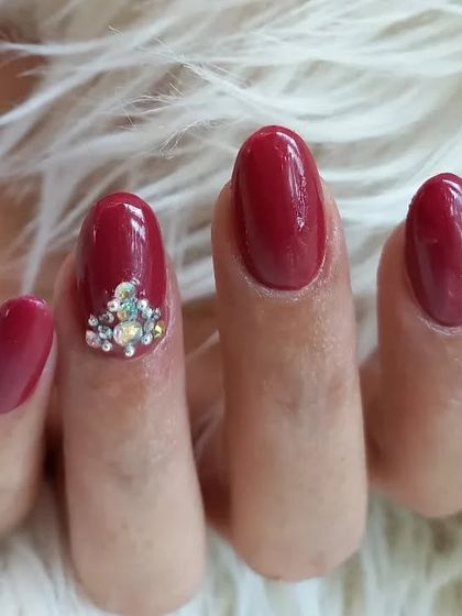 A close-up of the elegant rhinestone cluster on a glossy red nail.