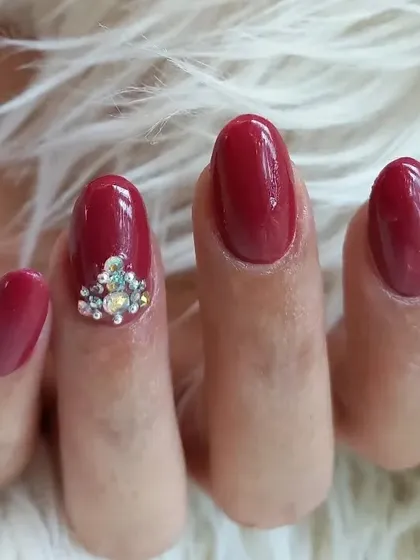 A close-up of the rhinestone accent on this deep red manicure. This detail shows how a small embellishment can add a significant touch of luxury and sophistication.