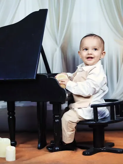 This little pianist is all smiles as he sits at the miniature grand piano.