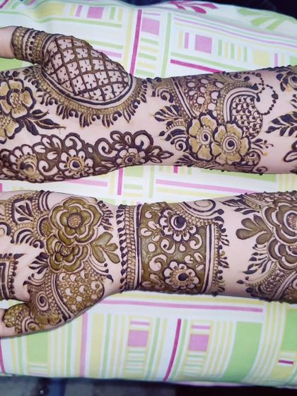 This design shows how you can have different patterns on each hand that still look like a perfect pair. One hand features a large jaali (net) pattern, while the other has more flowing floral work.