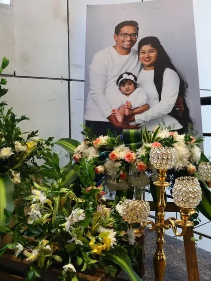 A personalized welcome area for a naming ceremony, featuring a large portrait of the family. I surrounded the photo with fresh floral arrangements and elegant candle stands to create a warm and inviting focal point.