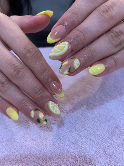A fresh and zesty summer design with yellow nails and accent nails featuring hand-painted lemon slices.
