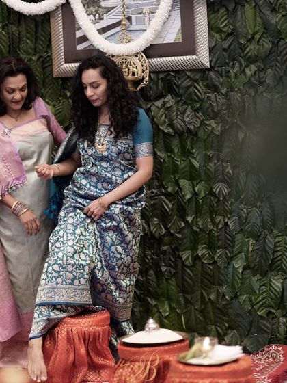 A mother and daughter share a moment in front of a unique backdrop made entirely of fresh coffee leaves from their family's estate in Coorg. This is the ultimate in personalized and locally-sourced decor.