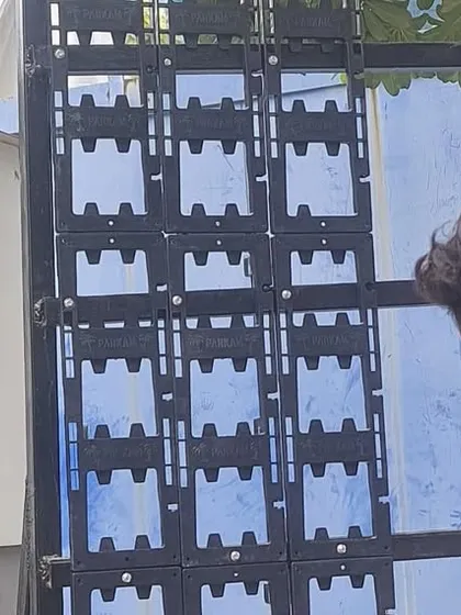 A team member installs the interlocking modular panels onto the MS frame. These panels are the backbone of the green wall, holding the soil and plants in place.