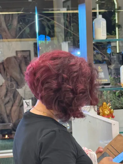 A side view of a bold transformation, combining a rich warm wine hair color with a fresh, modern bob cut.