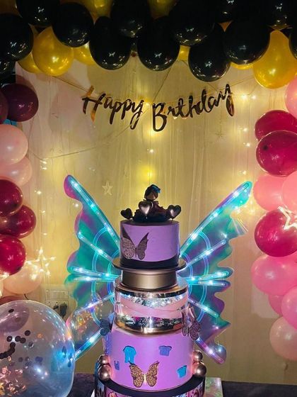 A gorgeous purple butterfly wing cake, captured in its party setting. The glowing wings and surrounding balloons show how my cakes create an amazing atmosphere.