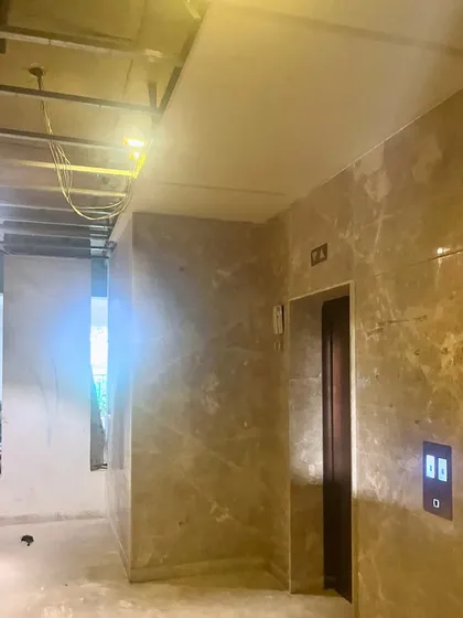 Even during construction, the form of the space begins to emerge. This image shows the installation of marble cladding in an elevator lobby, giving a first hint of the luxurious material palette that will define the finished project.