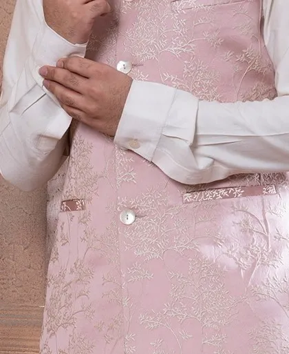 A detail shot of the rose pink bundi, showing the texture of the embroidery and the cuff of the shirt. Every element is carefully considered for a polished finish.