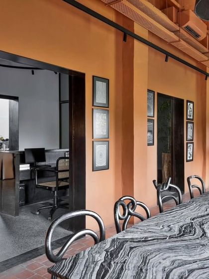 The office cafeteria or break area uses a warm terracotta color and sculptural chairs to create a welcoming and social atmosphere.