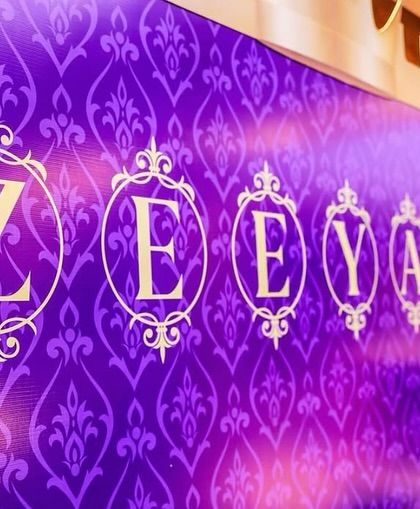 A close-up of the personalized name backdrop for Prince Zeeyan's royal-themed party. The elegant font and damask pattern in rich purple create a sophisticated and regal look.