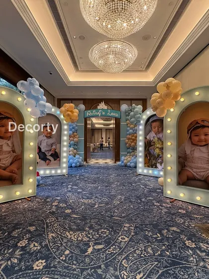 A stunning entryway featuring large, illuminated photo frames showcasing adorable pictures of the birthday boy, flanked by Disney characters.