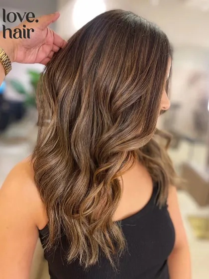 A side view of this sugar and honey balayage, highlighting the face-framing pieces and the seamless color melt.