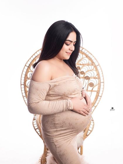 A simple and elegant portrait with the client seated in the boho peacock chair. The fitted beige gown and clean background create a modern and chic bohemian look.