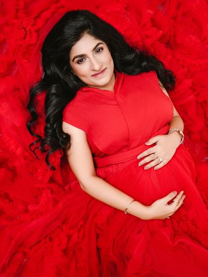 An overhead portrait that fills the frame with the vibrant red of her gown, creating a powerful and visually striking image of the mother-to-be.