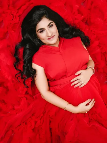 An overhead portrait that fills the frame with the vibrant red of her gown, creating a powerful and visually striking image of the mother-to-be.