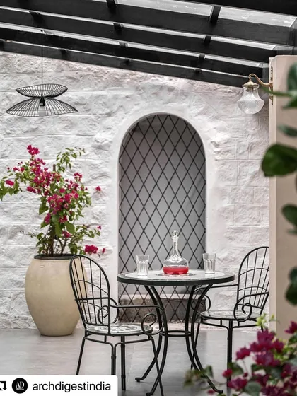 This tranquil patio space was a highlight of the Architectural Digest feature. The image captures the essence of indoor-outdoor living, with a textured stone wall, diamond-patterned grilles, and comfortable seating that creates a private, Mediterranean-inspired escape.