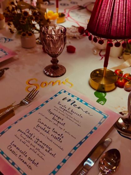 A close-up of the hand-painted menu and whimsical table setting for our "La Dolce Vita" themed dinner. The custom details make the experience truly personal.