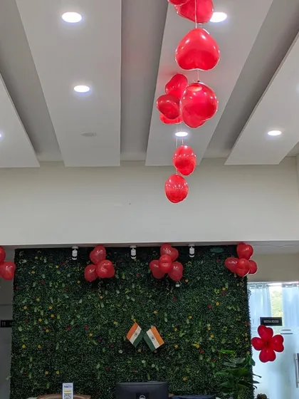 The reception area decorated for World Heart Day, featuring a green wall accented with heart balloons and two small Indian flags, blending a health awareness event with a touch of national pride.