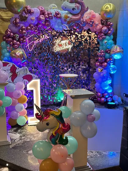 I love creating magical unicorn themes. This setup features a beautiful balloon arch over a shimmering sequin wall, a 'Happy Birthday' neon sign, and a light-up marquee number for that extra sparkle.