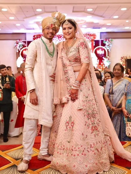 A full-length shot of the couple after their pheras. The bride's pastel lehenga and soft glam makeup are perfect for a modern wedding.