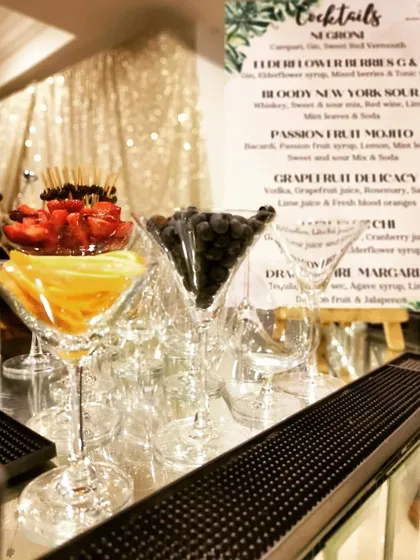 A display of fresh fruit garnishes in martini glasses, with our custom menu in the background. This image captures the essence of our preparation and attention to detail before an event.