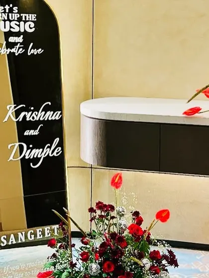 We create custom decor elements like this mirrored sign for a sangeet. The message "Let's turn up the music and celebrate love" sets a fun and personal tone for the event, complemented by bold red floral arrangements.