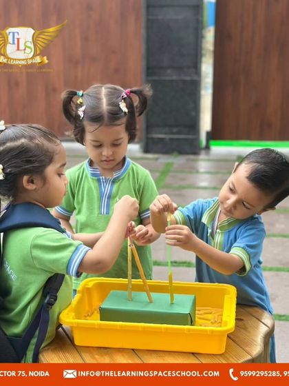 Three children work together on a fine motor skill activity. Collaborative play helps them learn to share, communicate, and solve problems as a team.
