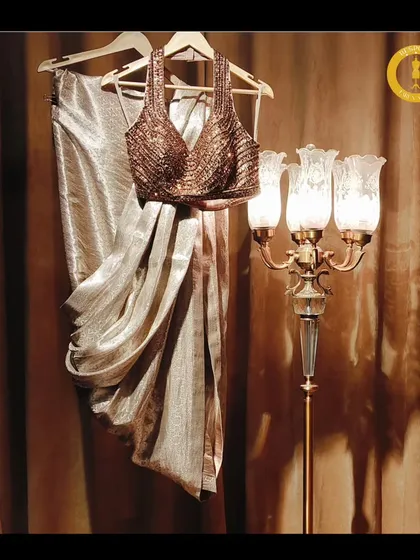 Elegance in every step. This shimmering gold drape saree with a halter neck blouse is laid out to showcase its beautiful fabric and intricate design.