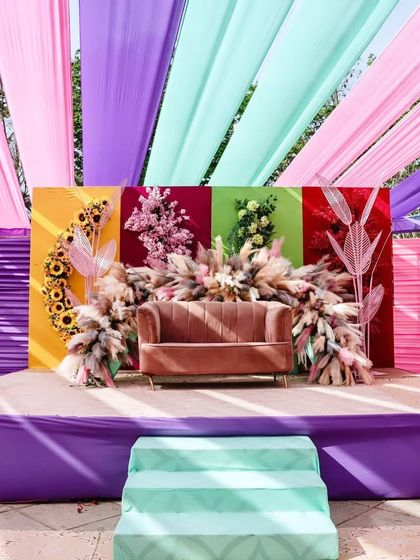 A closer look at the Haldi seating stage. We combined a plush sofa with a bold, color-blocked backdrop and arrangements of pampas grass and sunflowers for a modern, eclectic look.