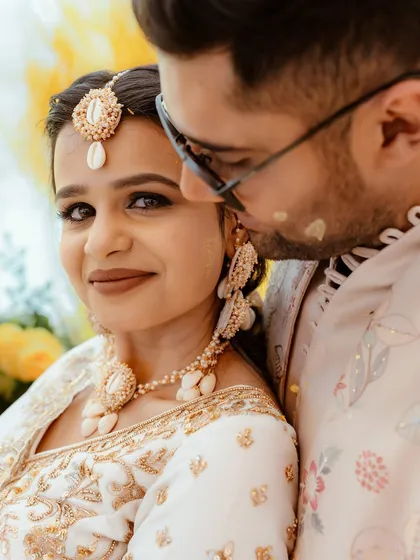 A sweet close-up of the couple, the groom playfully applying haldi. The bride's makeup is subtle and glowing.